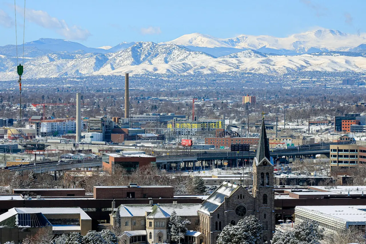 Denver cityscape with snow-covered Rocky Mountains behind it